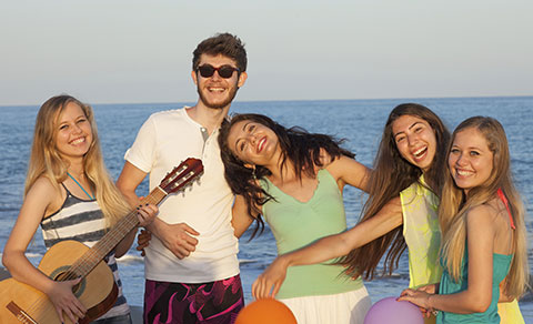 A group of people on a beach with a guitar.