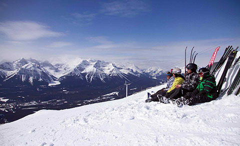 Skiiers taking a rest on the hill top in the snow. Alberta.